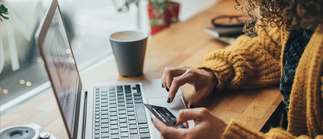 Woman at laptop holding credit card